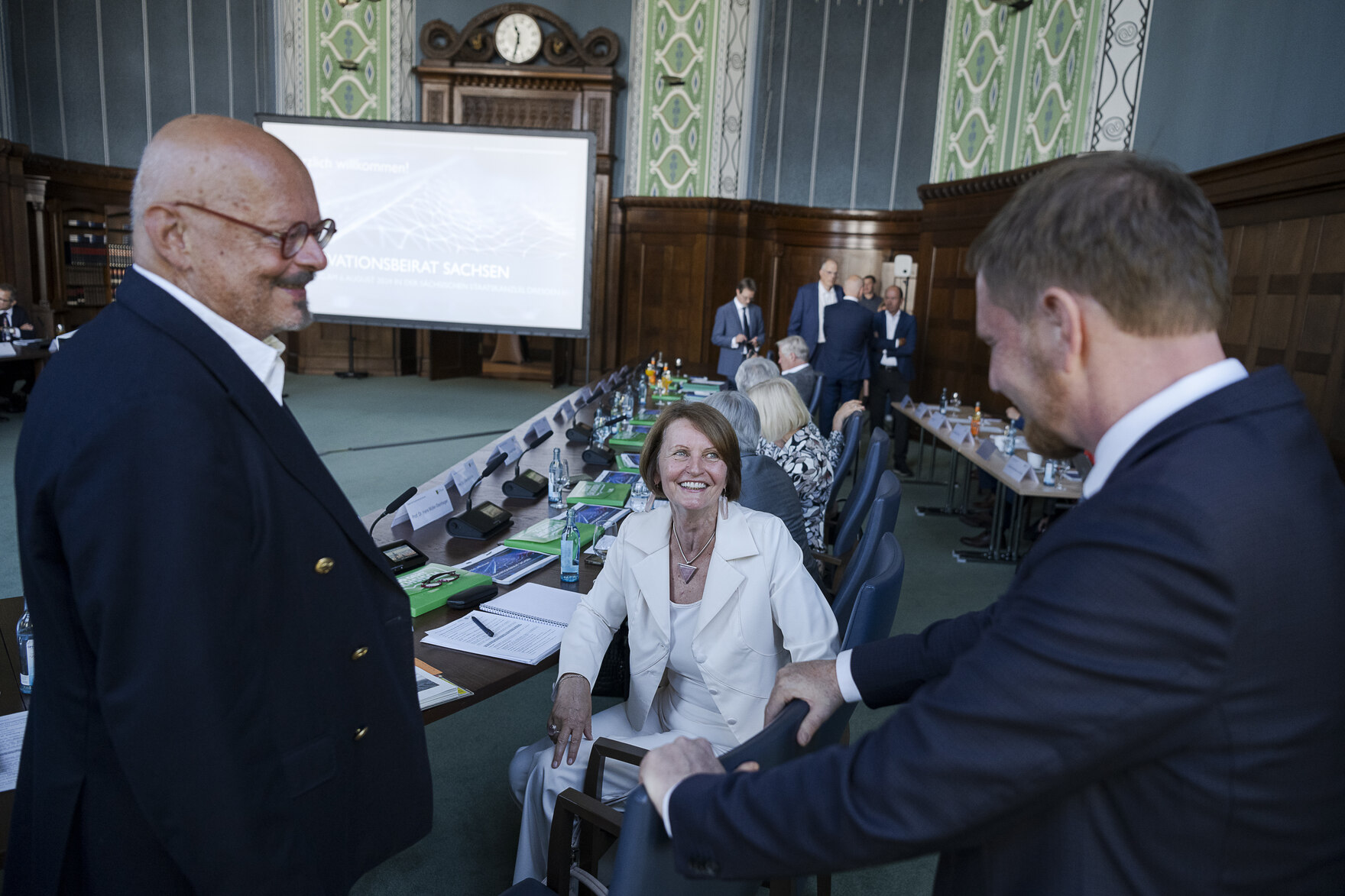 Zwei Männer unterhalten sich mit einer Frau in einem großen Saal.