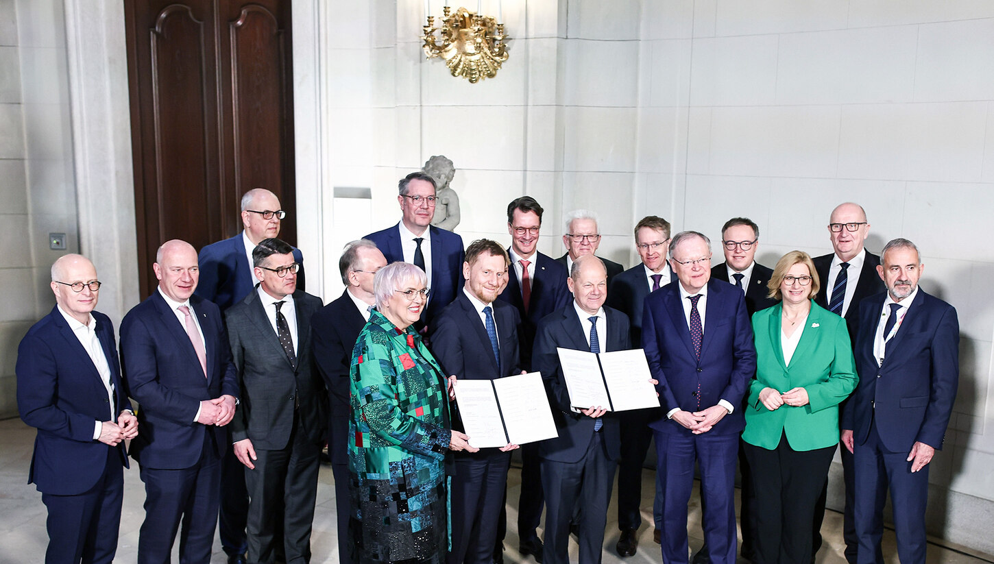 Männer und Frauen stehen in Reihe. Einige von ihnen halten einen Mappe in der Hand.